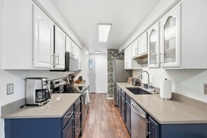 Une cuisine moderne avec des meubles blancs, une machine à café, un grille-pain et un évier.