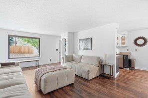 A modern living room with a large window, a sofa, a bench, and a small table. - Park House - Modern, Convenient, Redmond Retreat (Redmond)