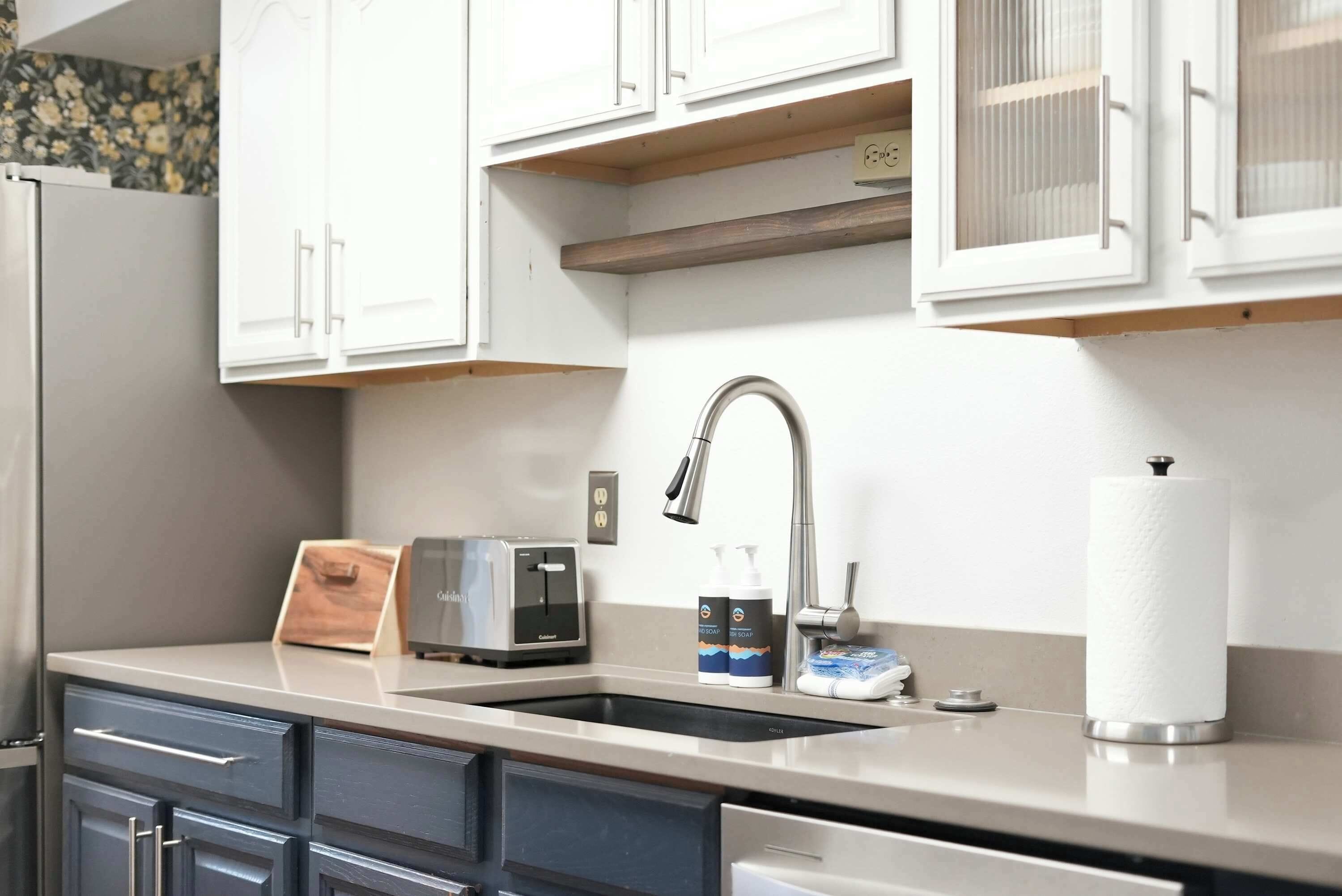 A kitchen with a double sink, a toaster, and a paper towel holder.