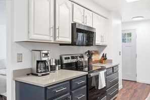A modern kitchen with white cabinetry, a stainless steel refrigerator, a coffee maker, and a kettle. - Park House - Modern, Convenient, Redmond Retreat (Redmond)