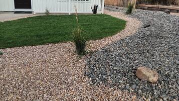 A residential property with a front yard featuring a gravel pathway, a small shrub, and a well-maintained lawn.