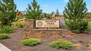 Ein Schild für den Quartz Park in der Stadt Redmond, umgeben von Bäumen und einem Spielplatz.