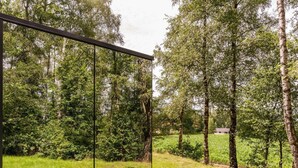 Eine moderne Glasarchitektur in einer natürlichen Umgebung mit Bäumen und Gras.