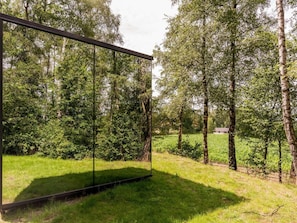 Eine moderne Glasarchitektur in einer natürlichen Umgebung mit Bäumen und Gras.