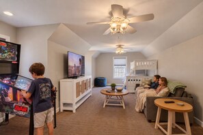 A living room with a television, a ceiling fan, a bunk bed, and a bean bag. - Forest Moon - Peaceful Pet-Friendly Wooded Retreat (Egg Harbor)