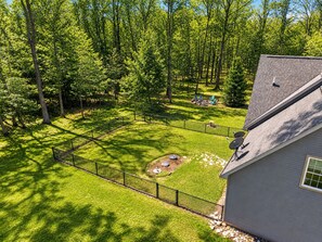 Ein umzäunter Garten mit Rasen, einer kleinen Terrasse und einem Haus mit Satellitenschüsseln.
