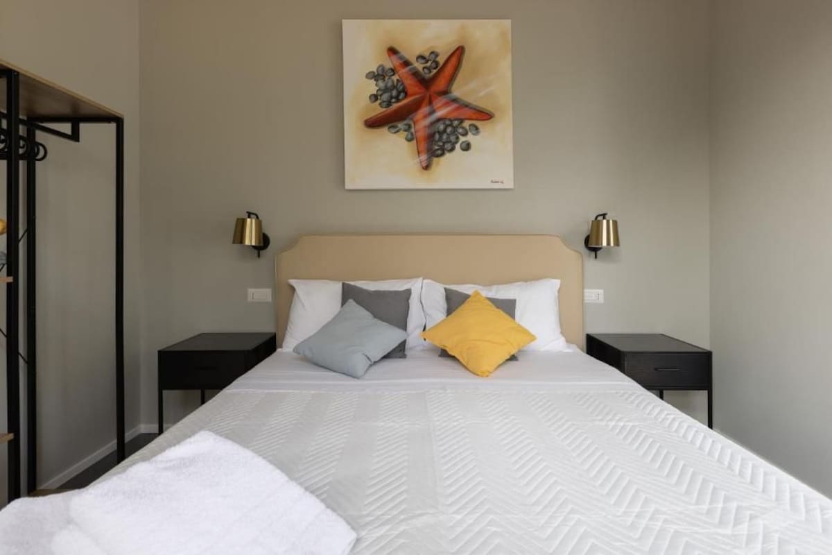 Une chambre d’hôtel comprenant un lit, deux tables de chevet, une tête de lit et une œuvre d’art accrochée au mur.