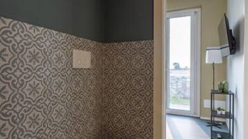 A bathroom with a toilet, sink, patterned wallpaper, and a view through an open door.