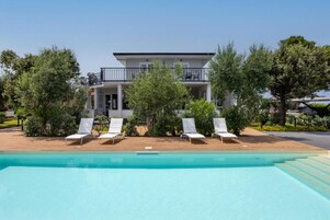 Un edificio moderno de dos pisos con piscina y sillones de descanso.