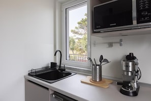 A kitchen with a black sink, a microwave above it, and a coffee machine on the counter.