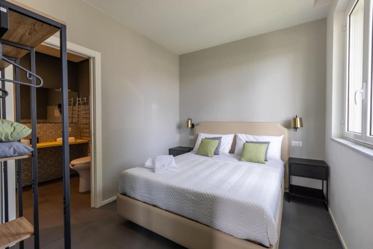 Une chambre d’hôtel avec un lit, des tables de chevet, une armoire et une fenêtre.