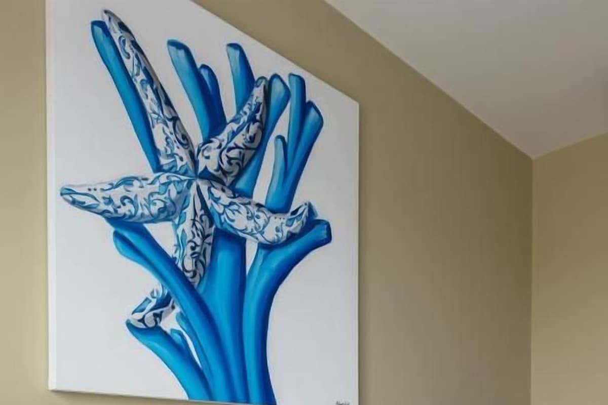 Une chambre d’hôtel avec un lit, deux oreillers, une table de chevet, une lampe et un tableau au mur.