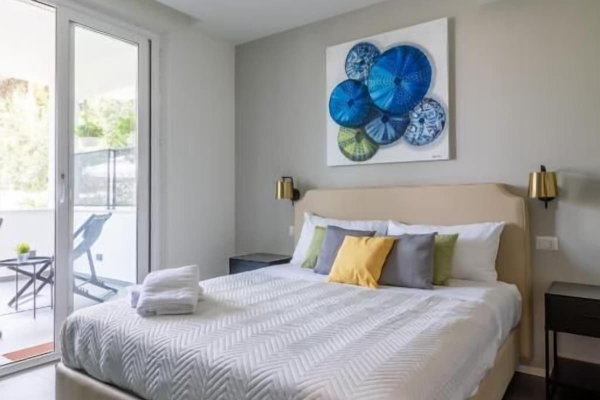 Une chambre moderne avec un grand lit, un ventilateur de plafond et une vue sur l’extérieur.