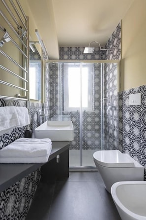 Une salle de bain avec une douche, deux lavabos et des murs décorés de motifs.