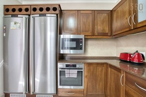 A kitchen with two stainless steel refrigerators, a microwave, an oven, wooden cabinets, and a red kettle. - 3 BR Penthouse with Terrace & Country Views & WIFI (Żebbuġ)
