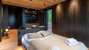 A bedroom with a bed, bedside tables, and a view of the outdoors. - Wilsumer Berge Resort- Nokken Forest Cabin by Interhome (Wilsum)