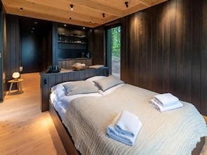 Een slaapkamer met een bed, nachtkastjes en uitzicht op de omgeving.