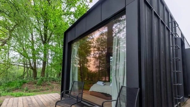 A modern outdoor room with a bed, two chairs, and a small table. - Wilsumer Berge Resort- Nokken Forest Cabin by Interhome (Wilsum)