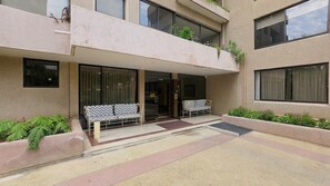 A building with a covered entrance, two outdoor seating areas, and a small garden.