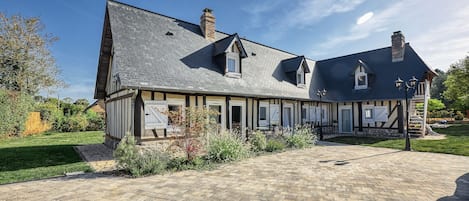 Une maison traditionnelle Ă colombages, dotĂ©e dâune allĂ©e pavĂ©e et dâun jardin bien entretenu.