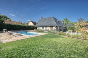 Una casa amb piscina, gespa ben cuidada i zona de jardí.
