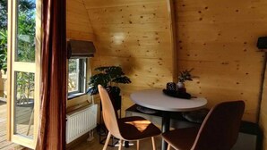 A wooden interior with a round table and chairs, a window with curtains, and a radiator. - Wilsumer Berge Resort - Wood Lodge by Interhome (Wilsum)