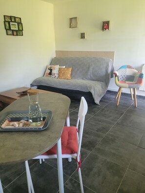 Una zona de menjador amb taula, cadires i un sofà al fons.