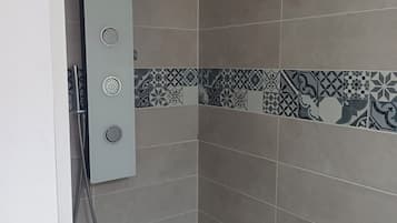 Een douchecabine met een handdouche en een bedieningspaneel aan de muur.