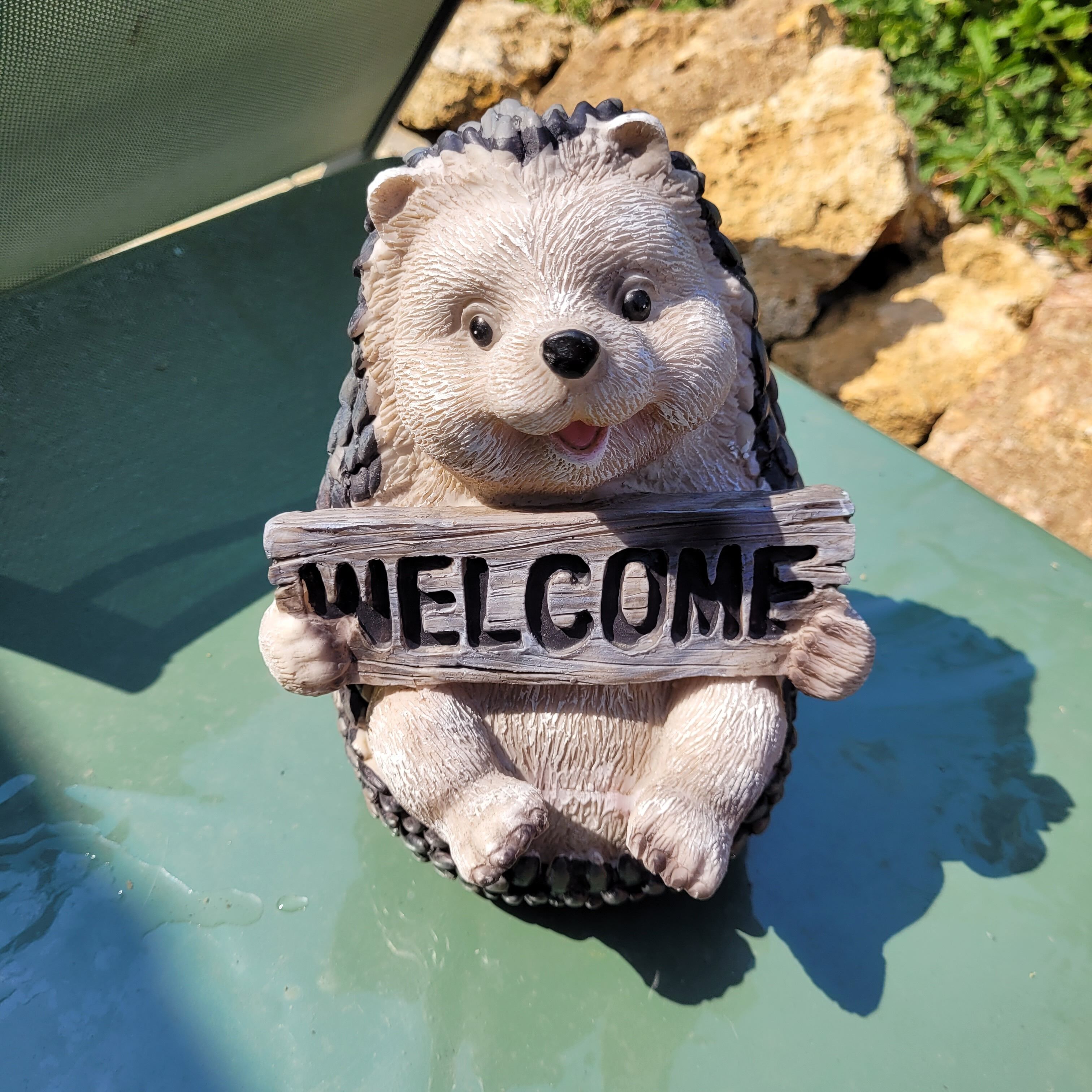 A hedgehog figurine holding a sign that reads 'WELCOME'.