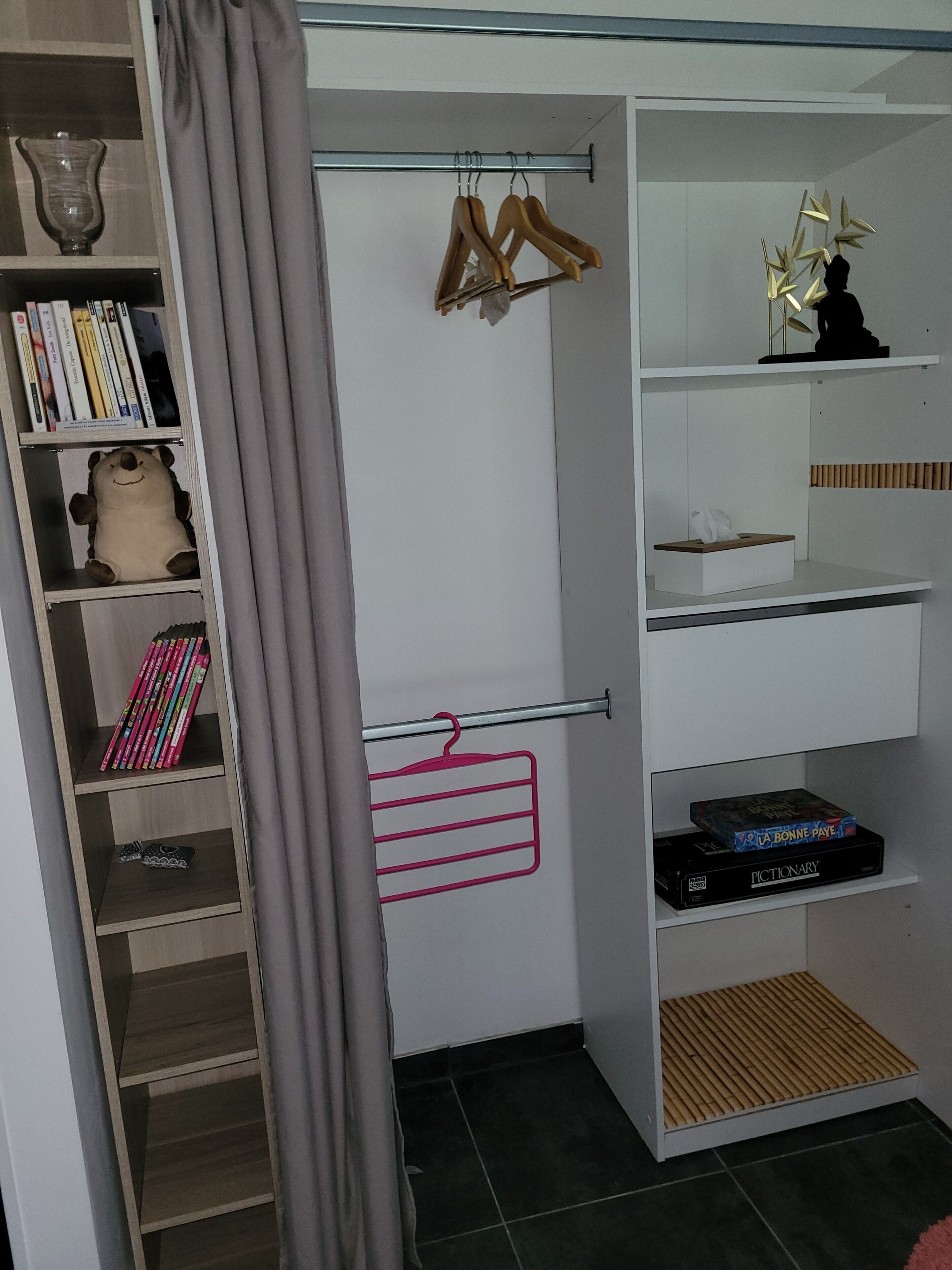 Ein Zimmer mit einem Schrank, der Regale, eine Kleiderstange und ein Schuhfach bietet.