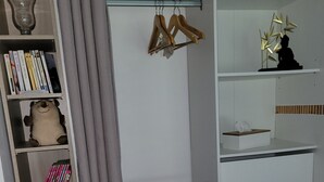 A room with a wardrobe containing shelves, a hanging rod, and a shoe rack.
