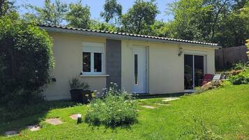 Een gelijkvloers huis met een plat dak, een voordeur en een klein voortuintje.