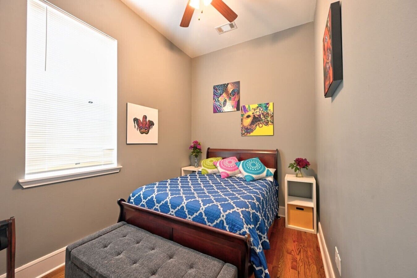 A bedroom with a bed, bedside tables, a bench, and artwork on the walls.