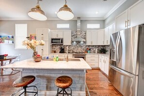 A modern kitchen with a central island, stainless steel appliances, and pendant lighting. - 2BR Home 1 Block to Streetcar, Near French Quarter (New Orleans)