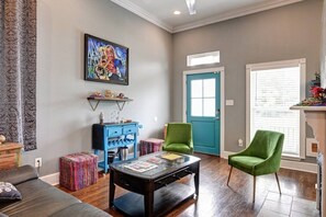 A living room with a sofa, a coffee table, a blue cabinet, a green armchair, and a door with a window. - 2BR Home 1 Block to Streetcar, Near French Quarter (New Orleans)
