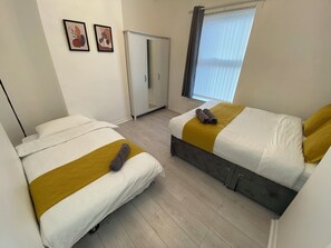 Une chambre d’hôtel avec deux lits, une armoire et une fenêtre avec des stores.