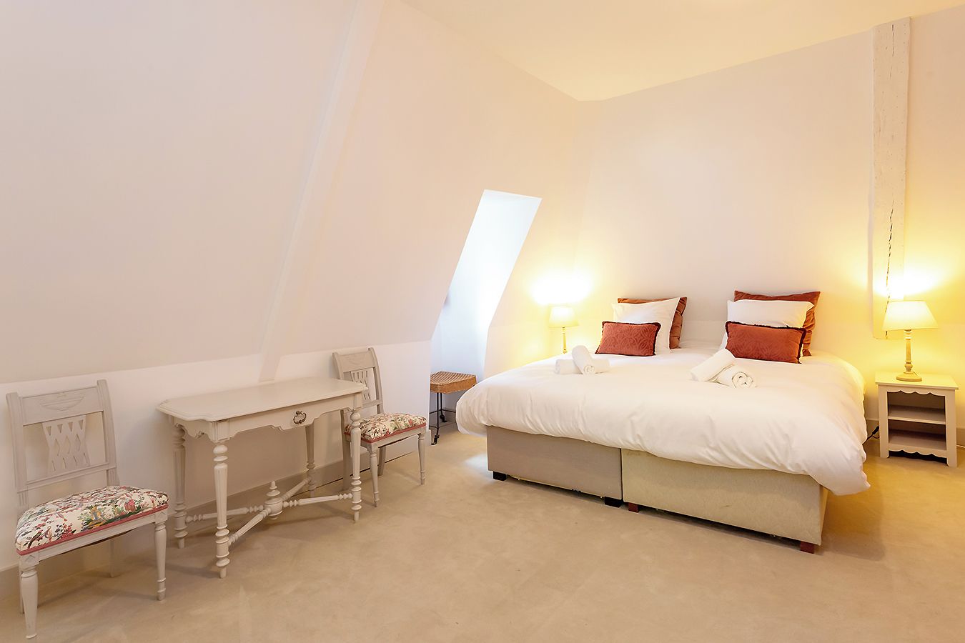 Une chambre à coucher avec un lit, des tables de chevet, un bureau et une chaise.