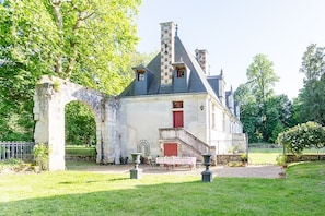 A historic building with a stone archway, a red door, and a staircase leading to the entrance. - Manor House Near the Castles of the Loire Valley (Neuillé-Pont-Pierre)