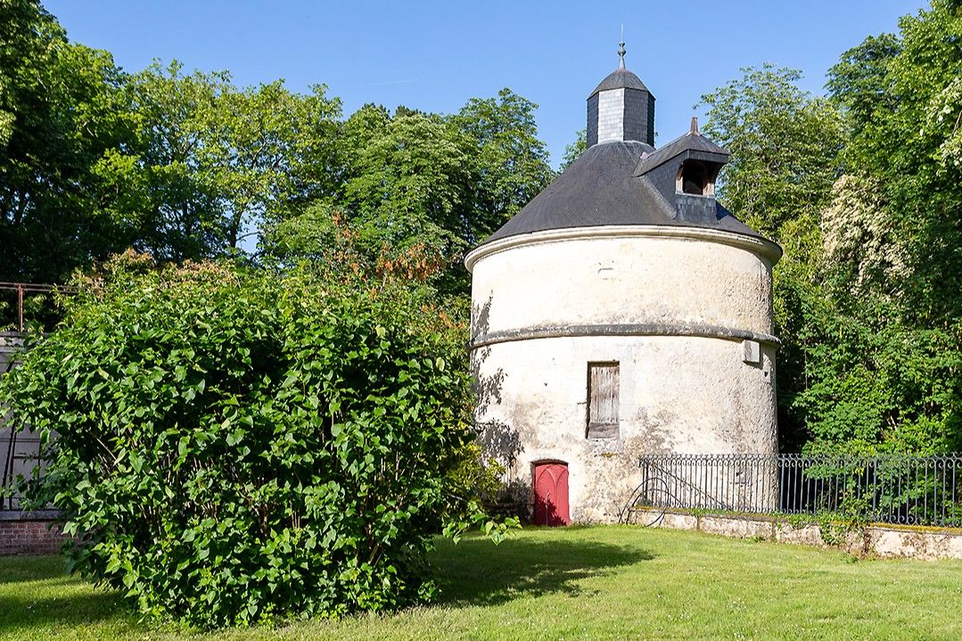 A circular building with a conical roof, surrounded by greenery.