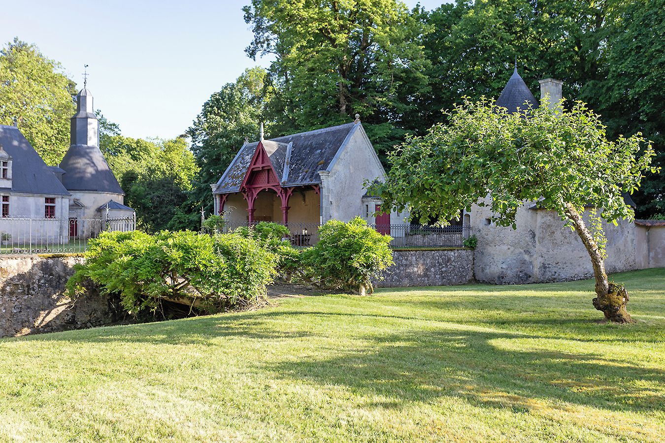 A traditional building with a red roof, surrounded by a well-maintained lawn and mature trees.