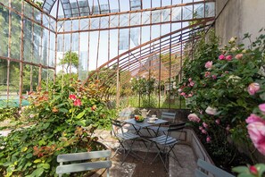 A greenhouse with a glass roof, a table with chairs, and blooming roses. - Manor House Near the Castles of the Loire Valley (Neuillé-Pont-Pierre)