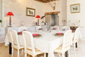 A dining room with a large table set for six, white chairs, and red table settings. - Manor House Near the Castles of the Loire Valley (Neuillé-Pont-Pierre)