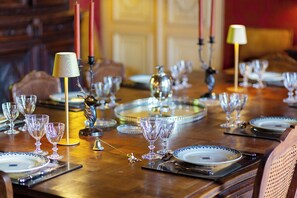 A dining table set with multiple wine glasses, plates, and cutlery, with candles and a lamp on the table. - Manor House Near the Castles of the Loire Valley (Neuillé-Pont-Pierre)