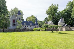 A large estate with multiple buildings, including a prominent tower and a smaller structure with a conical roof. - Manor House Near the Castles of the Loire Valley (Neuillé-Pont-Pierre)