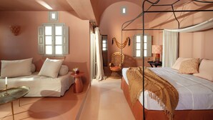 Un dormitorio con cama, sofá, sillón y una mesita.