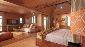 A spacious bedroom with a four-poster bed, a sofa, a television, and a balcony view. - Terra Verde Oia Suites - Terracote Grand Suite Sea View with Outdoor Jetted Tub (Oia)