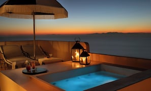 Ein Balkon mit Whirlpool, Liegestühlen und einem Tisch mit Getränken und Obst.