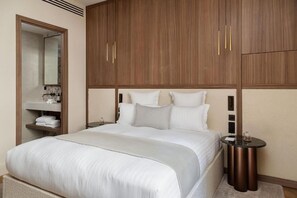 Une chambre d’hôtel comprenant un lit, une armoire, un miroir, une table de chevet et une petite table ronde.