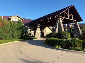 A building with a stone facade, a covered entrance, and a curved driveway. - Wave Pointe Marina and Resort (Sturgeon Bay)