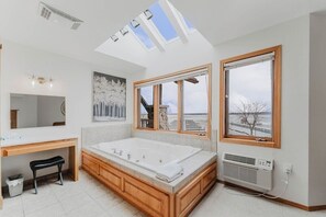 A modern bathroom with a large bathtub, skylights, and a view of the outdoors.